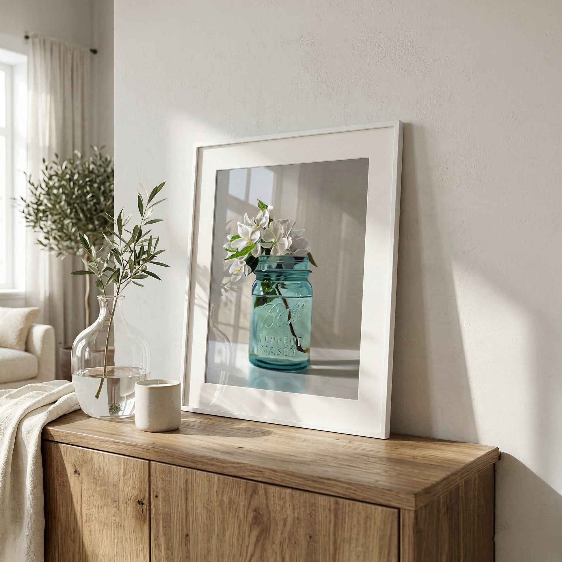 Framed fine art print of white apple blossoms in a vintage blue mason jar on a wooden cabinet.