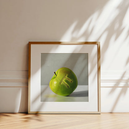 Framed fine art print of a green apple with a carved pi symbol, leaning against a white wall.