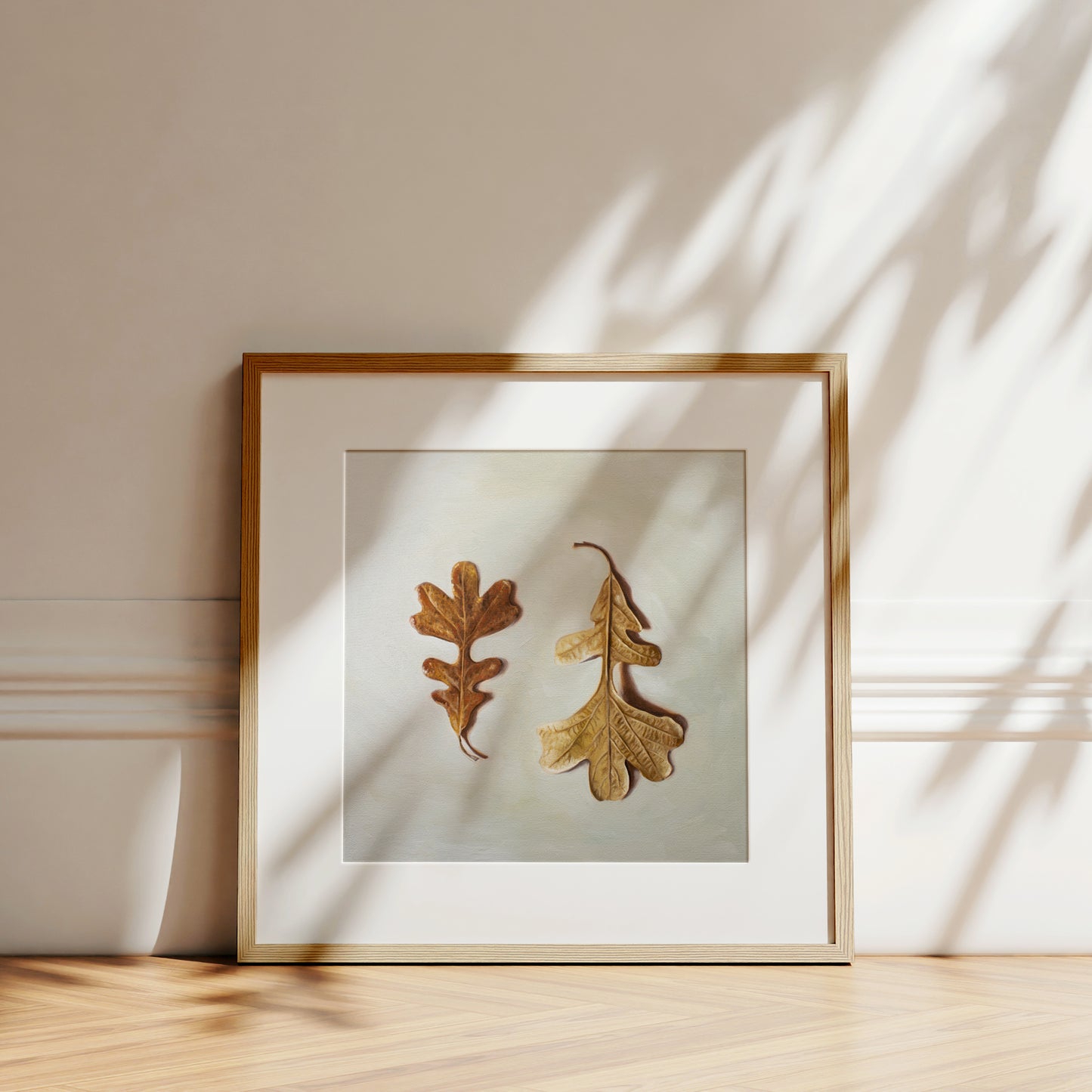 Autumn Oak Tree Leaves Fine Art Print by Lauren Pretorius: a duo of Oak Tree leaves laying on a light surface. One of the leaves faces upwards, while the other is flipped over and upside down.