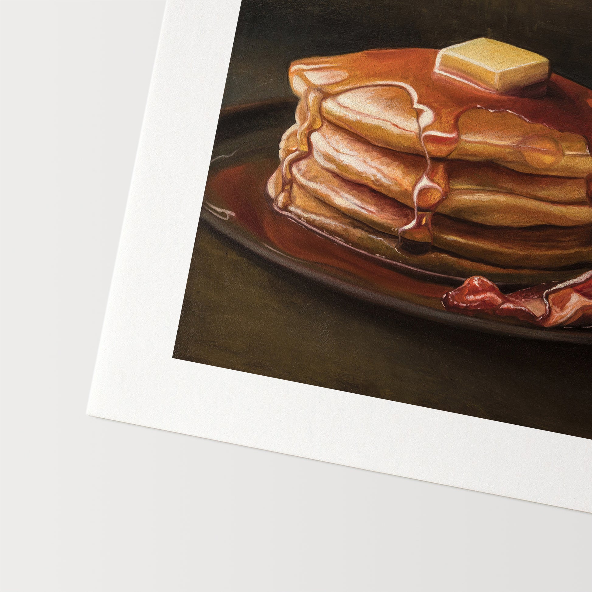 Bacon & Pancakes Fine Art Print by Lauren Pretorius: a stack of pancakes with butter and syrup resting on a plate, there are a couple of slices of bacon off to the right.