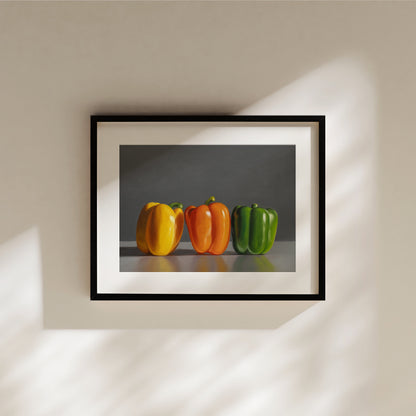 Framed fine art print of three bell peppers: yellow, orange, and green, on a dark background.