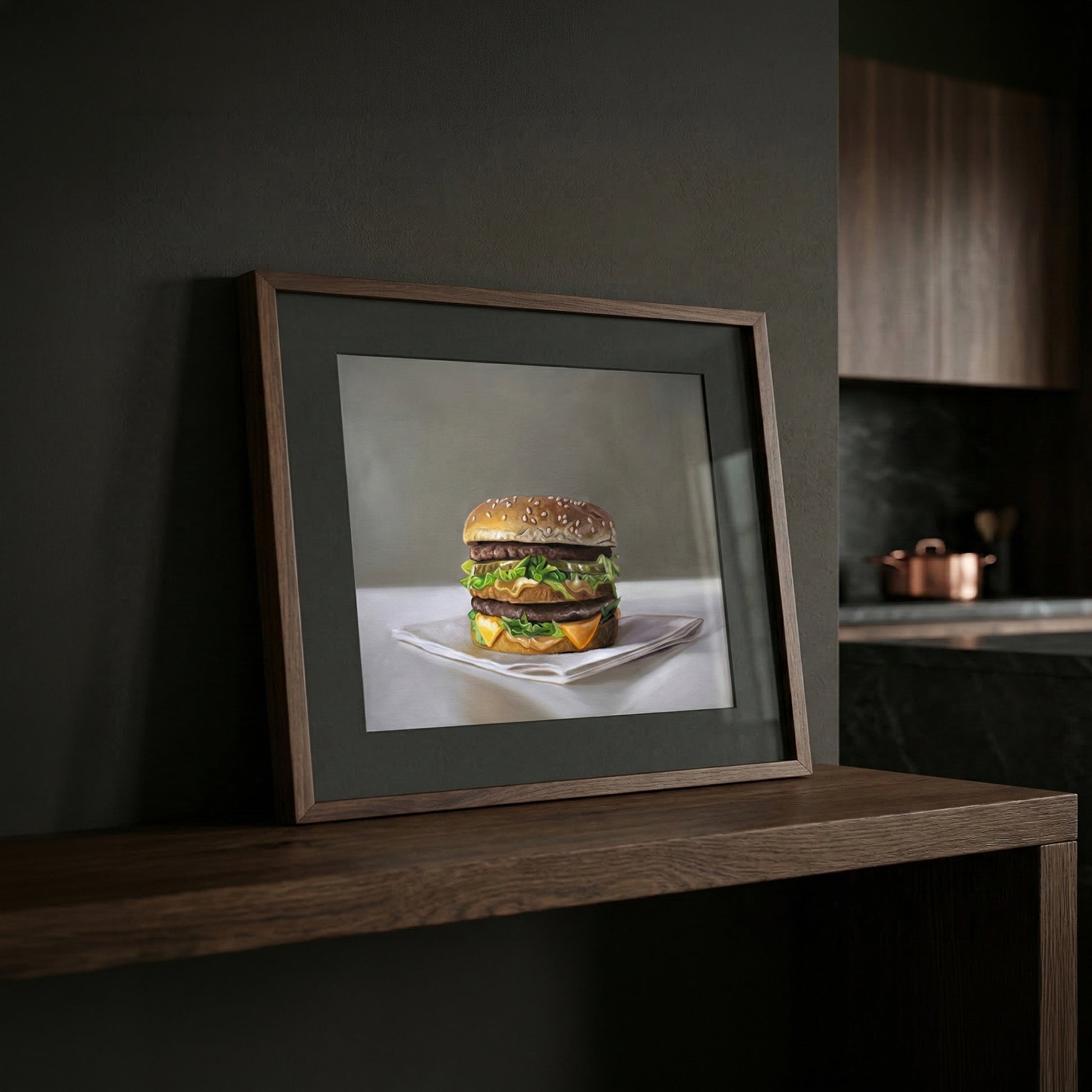 Framed Big Mac burger fine art print on a dark wooden shelf in a modern kitchen.