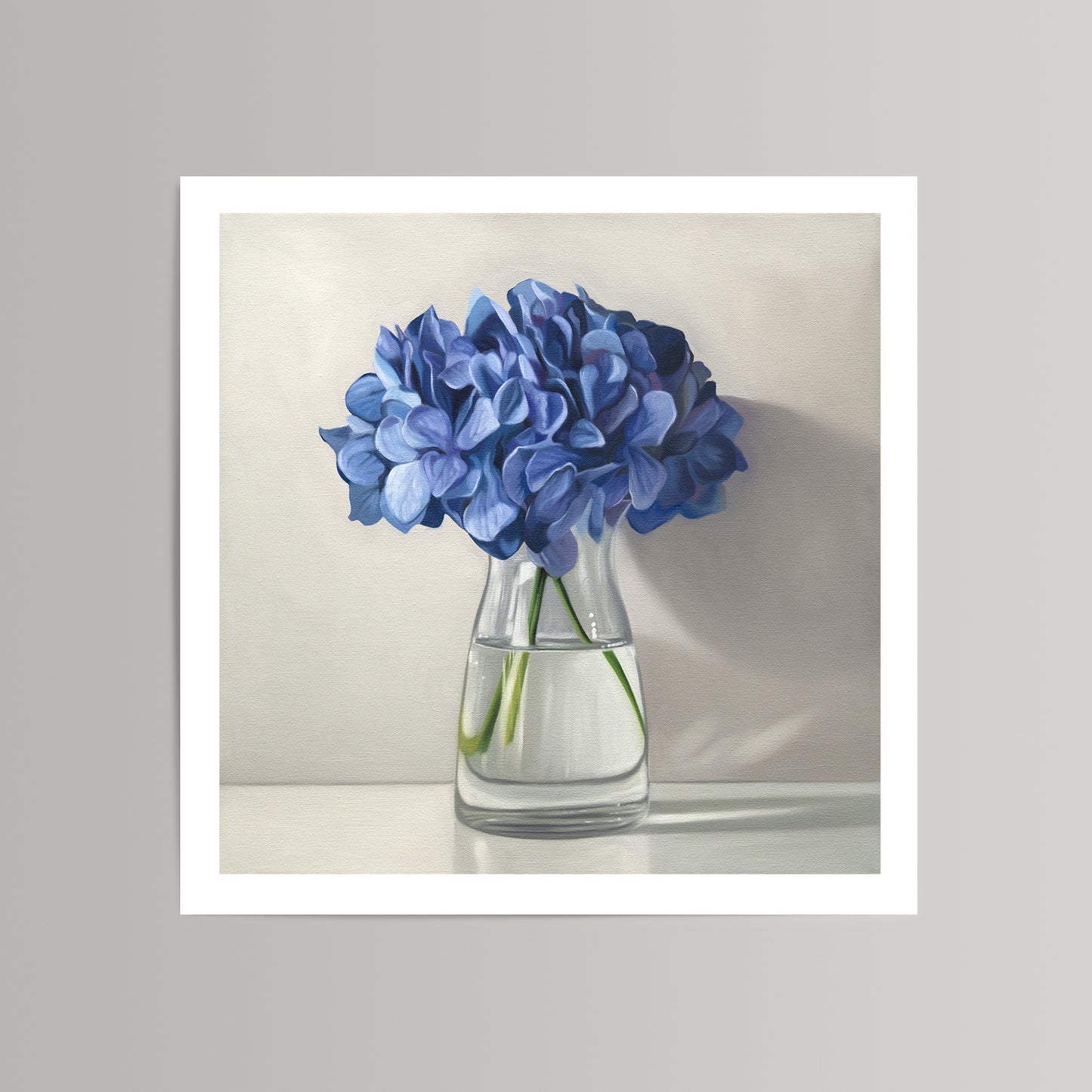 Fine art print of vibrant blue hydrangeas in a clear glass vase, on a light background.