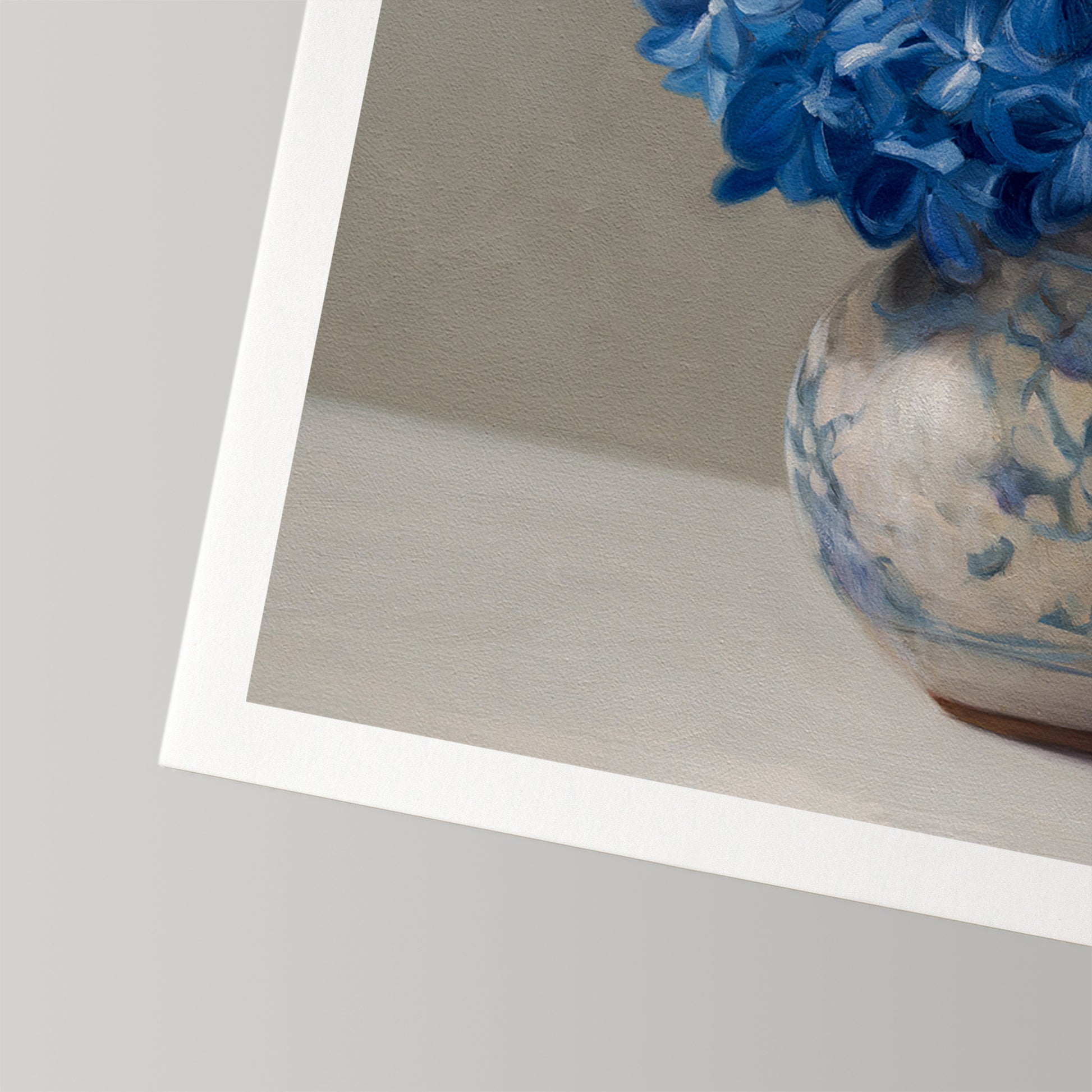 Fine art print of blue hydrangeas in a white and blue patterned vase, with a white border.