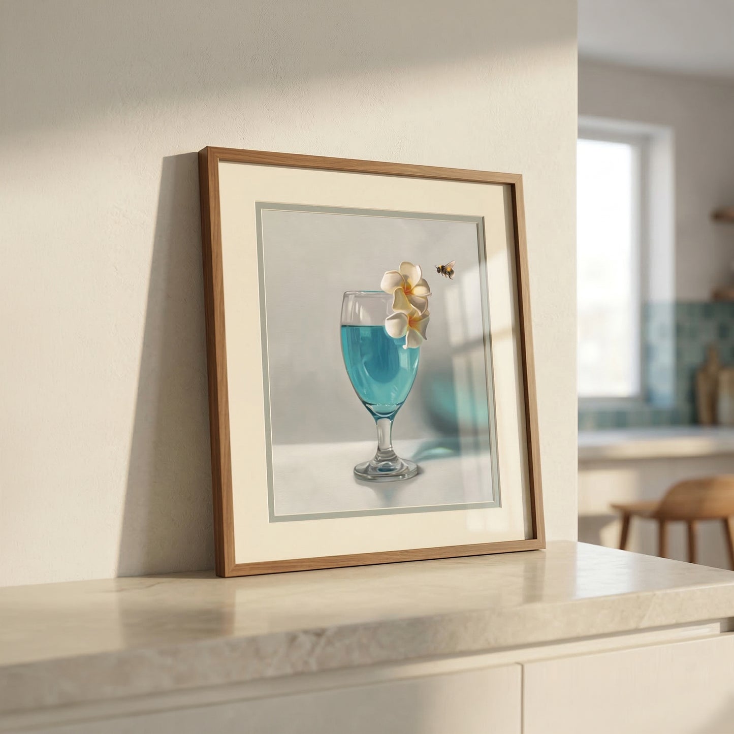 Framed fine art print of a blue drink with plumeria flowers and a bumblebee, on a kitchen counter.