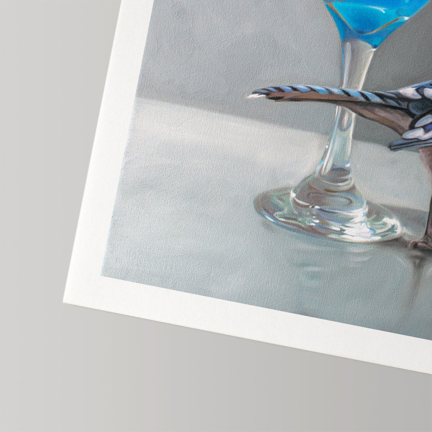 Fine art print featuring a blue jay perched on a martini glass with a vibrant blue drink, on textured cotton rag paper.