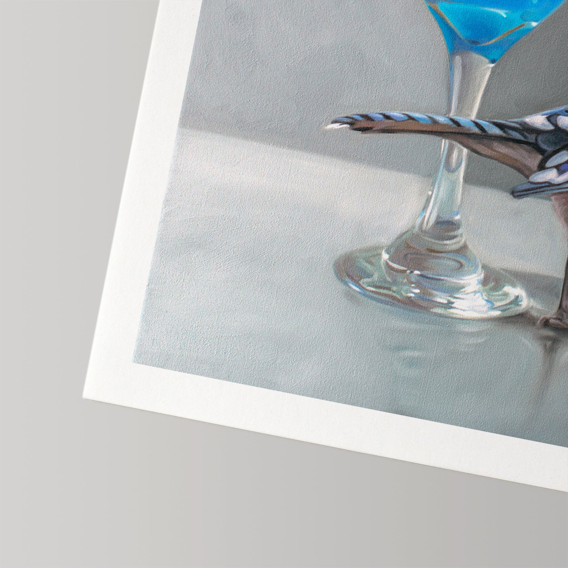 Fine art print featuring a blue jay perched on a martini glass with a vibrant blue drink, on textured cotton rag paper.