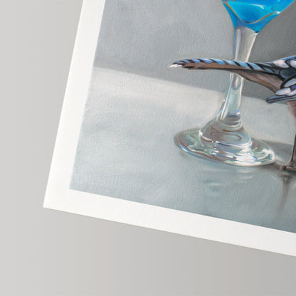 Fine art print featuring a blue jay perched on a martini glass with a vibrant blue drink, on textured cotton rag paper.