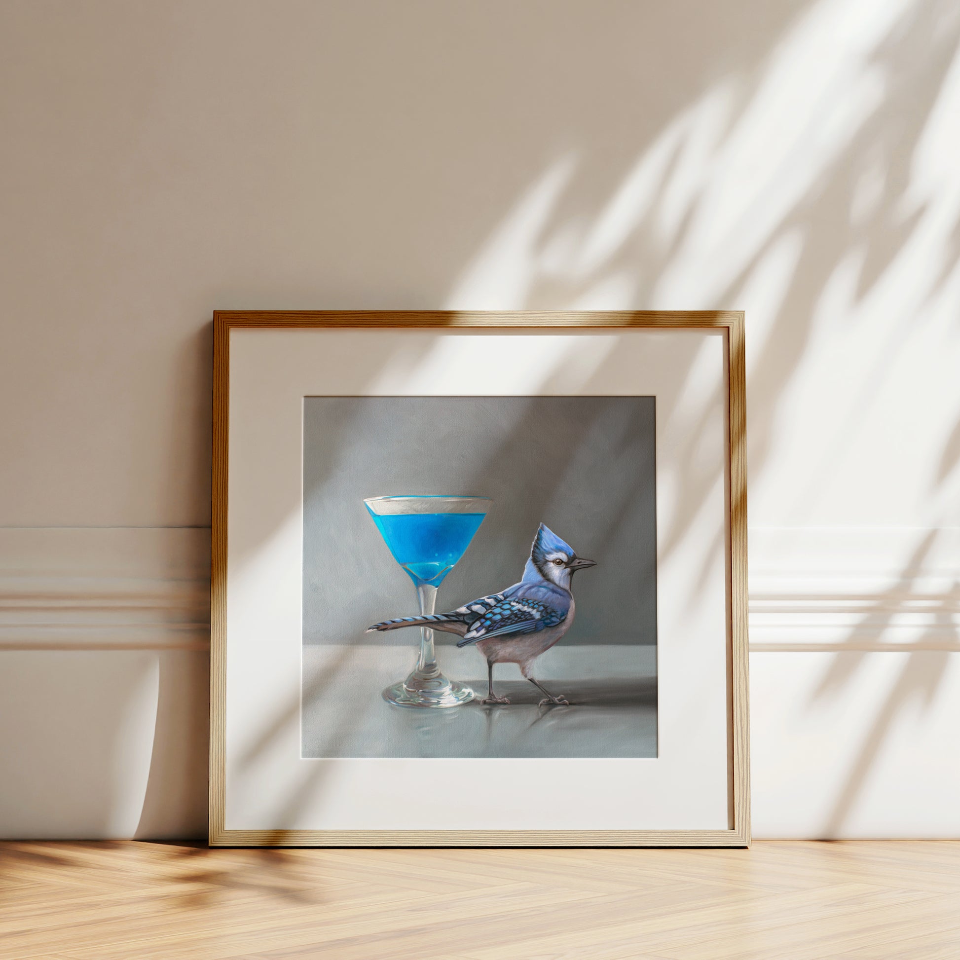 Framed fine art print featuring a blue jay next to a blue martini in a coupe glass.