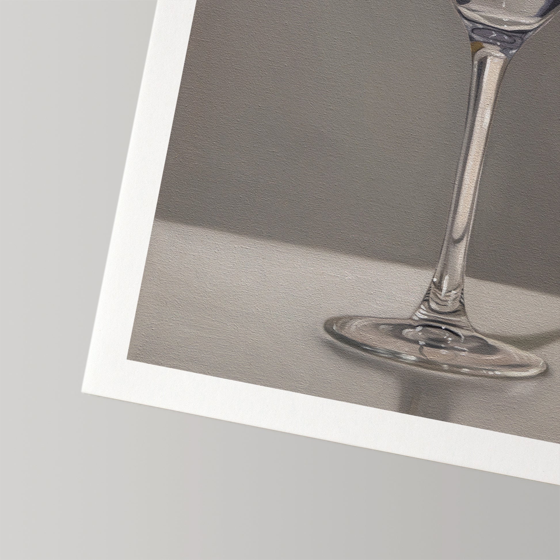 Close-up of a fine art print featuring a clear martini glass stem and base on a gray background with a white border.