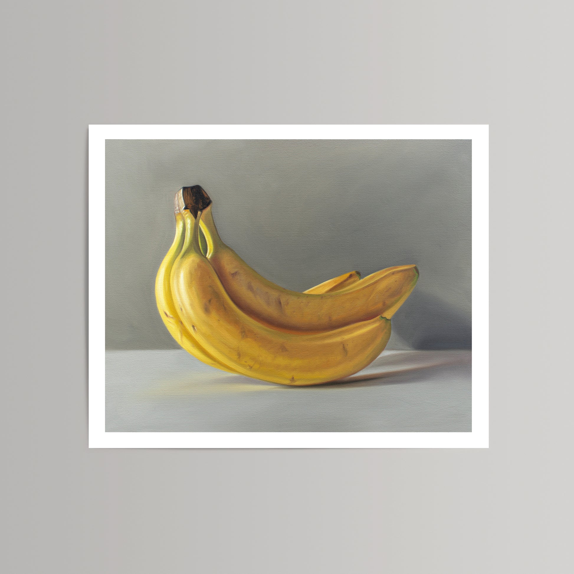 Fine art print of a bunch of ripe yellow bananas with a white border, on a gray background.