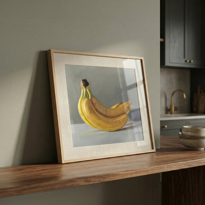 Still life fine art print of a bunch of yellow bananas in a light wood frame, leaning on a wooden shelf.