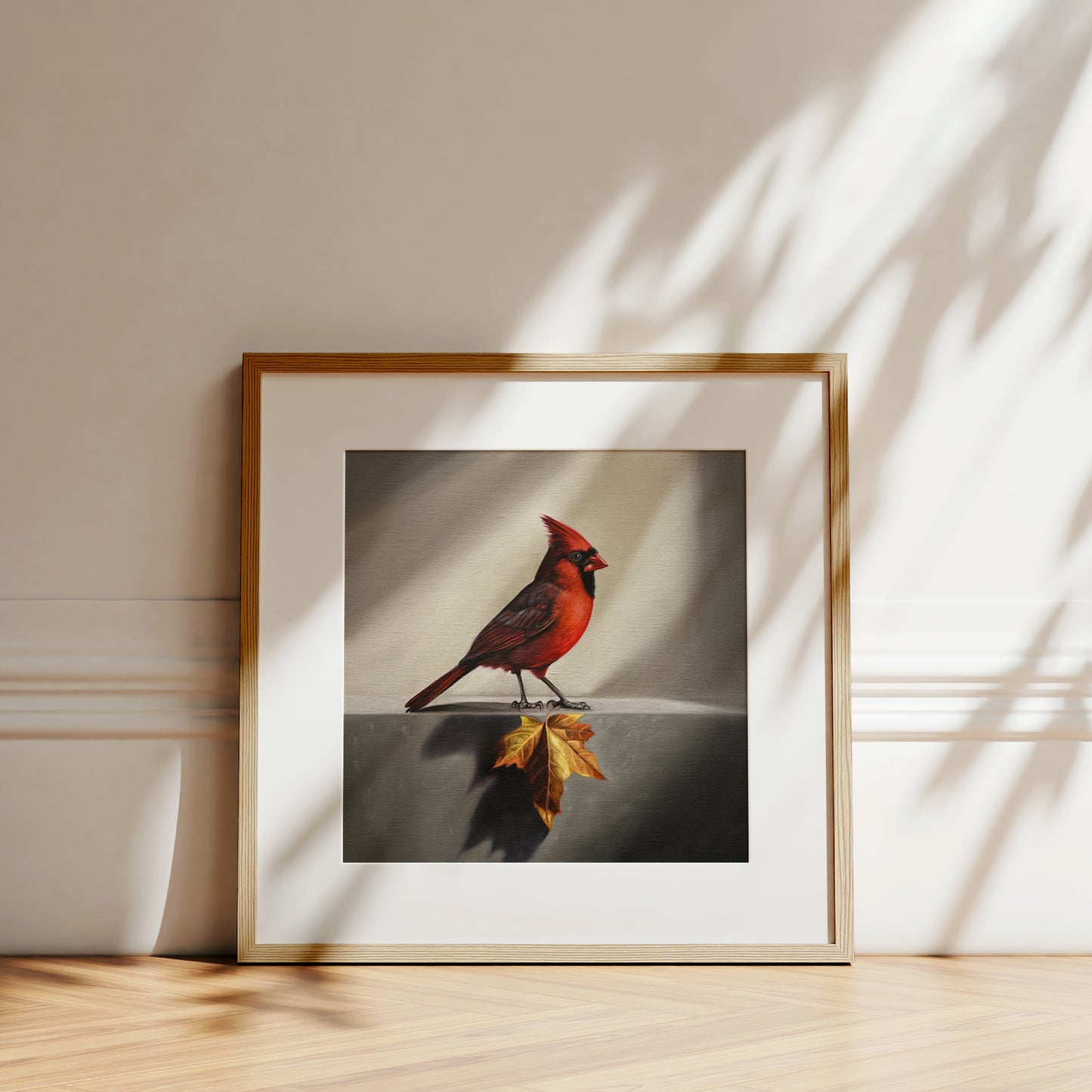 Framed fine art print of a vibrant red cardinal standing on an autumn maple leaf, with a white mat.