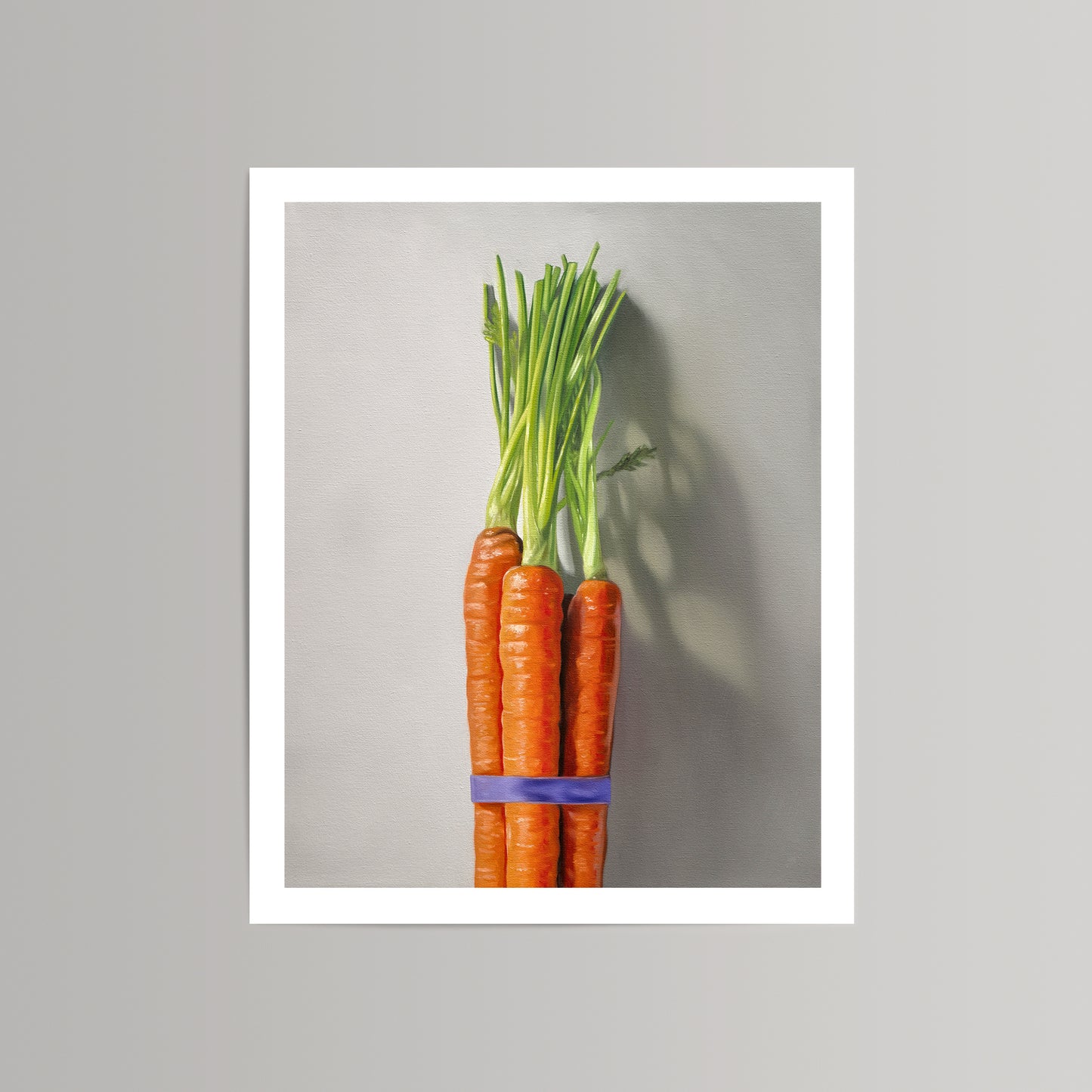 Fine art print of a vibrant orange carrot bunch with green tops, tied with a purple band, on a light gray background.