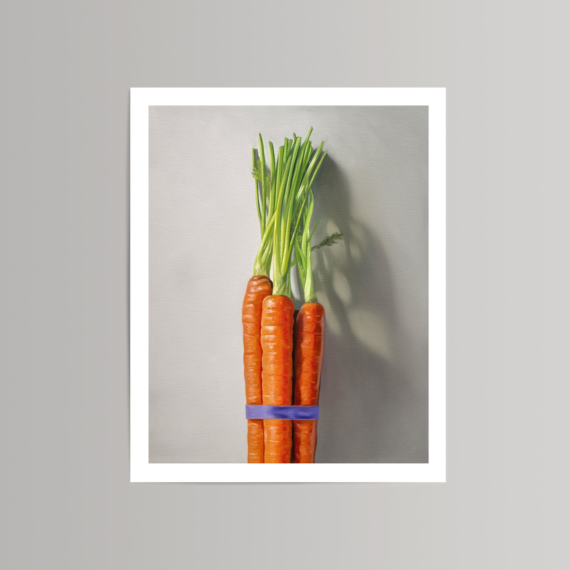 Fine art print of a vibrant orange carrot bunch with green tops, tied with a purple band, on a light gray background.