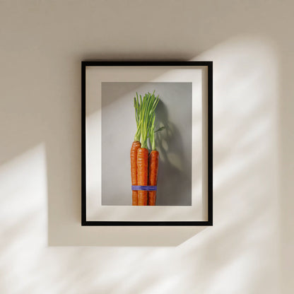 Framed fine art print of a vibrant orange carrot bunch with green tops, tied with a blue band.