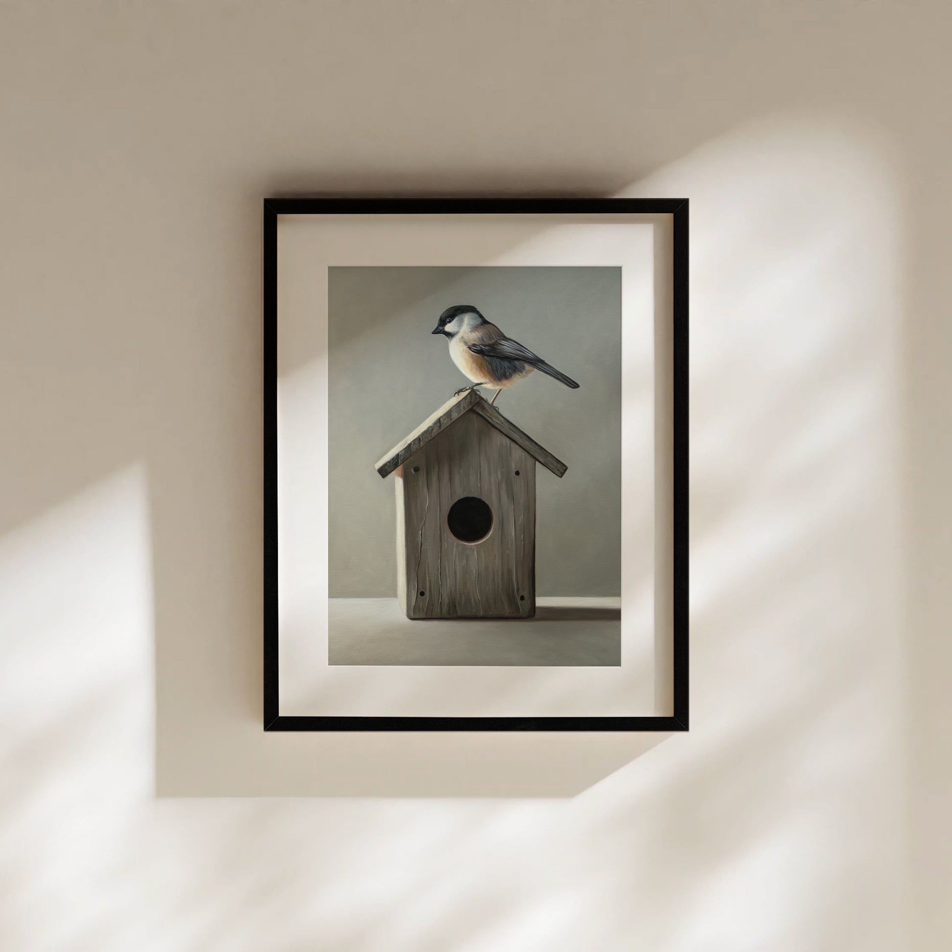 Chickadee & Birdhouse Fine Art Print by Lauren Pretorius: a Chickadee perched don top of a wooden bird house resting on a white surface with grey background.