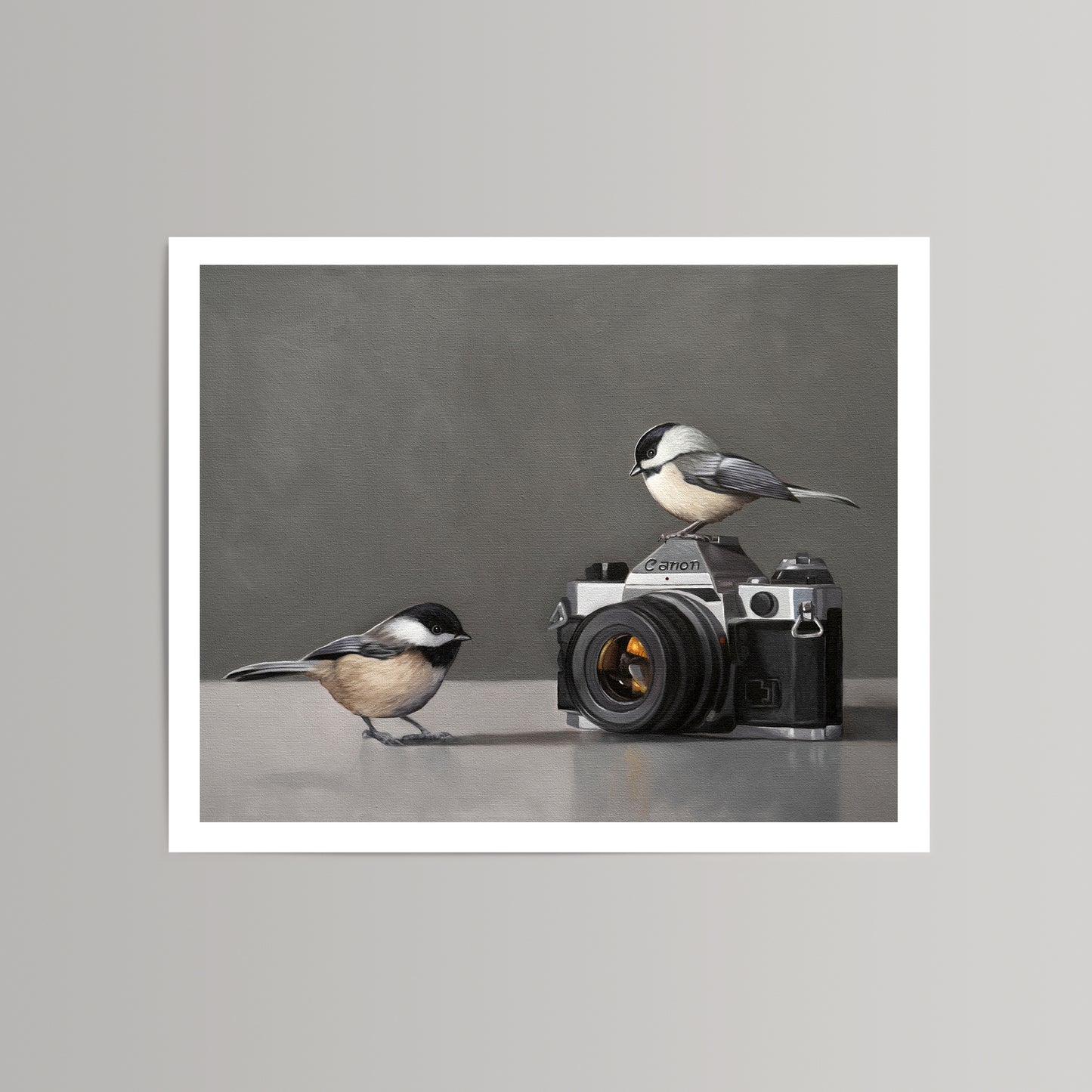 Fine art print: two black-capped chickadees, one perched on a vintage Canon camera, on a grey background.