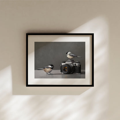 Fine art print of two chickadees with a vintage Canon camera, framed in black.