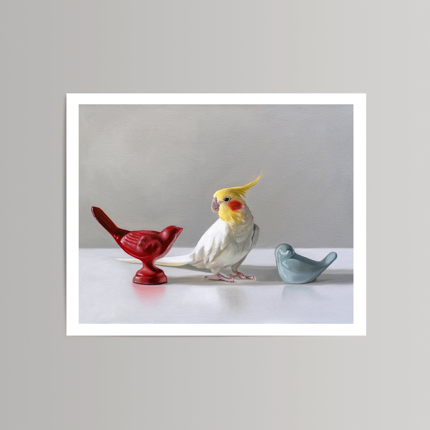 Fine art print of a white cockatiel bird between red and blue ceramic bird figurines.