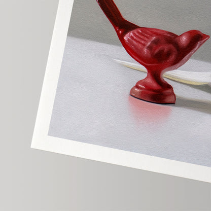 Fine art print of a glossy red bird figurine on a white surface, with a white border.