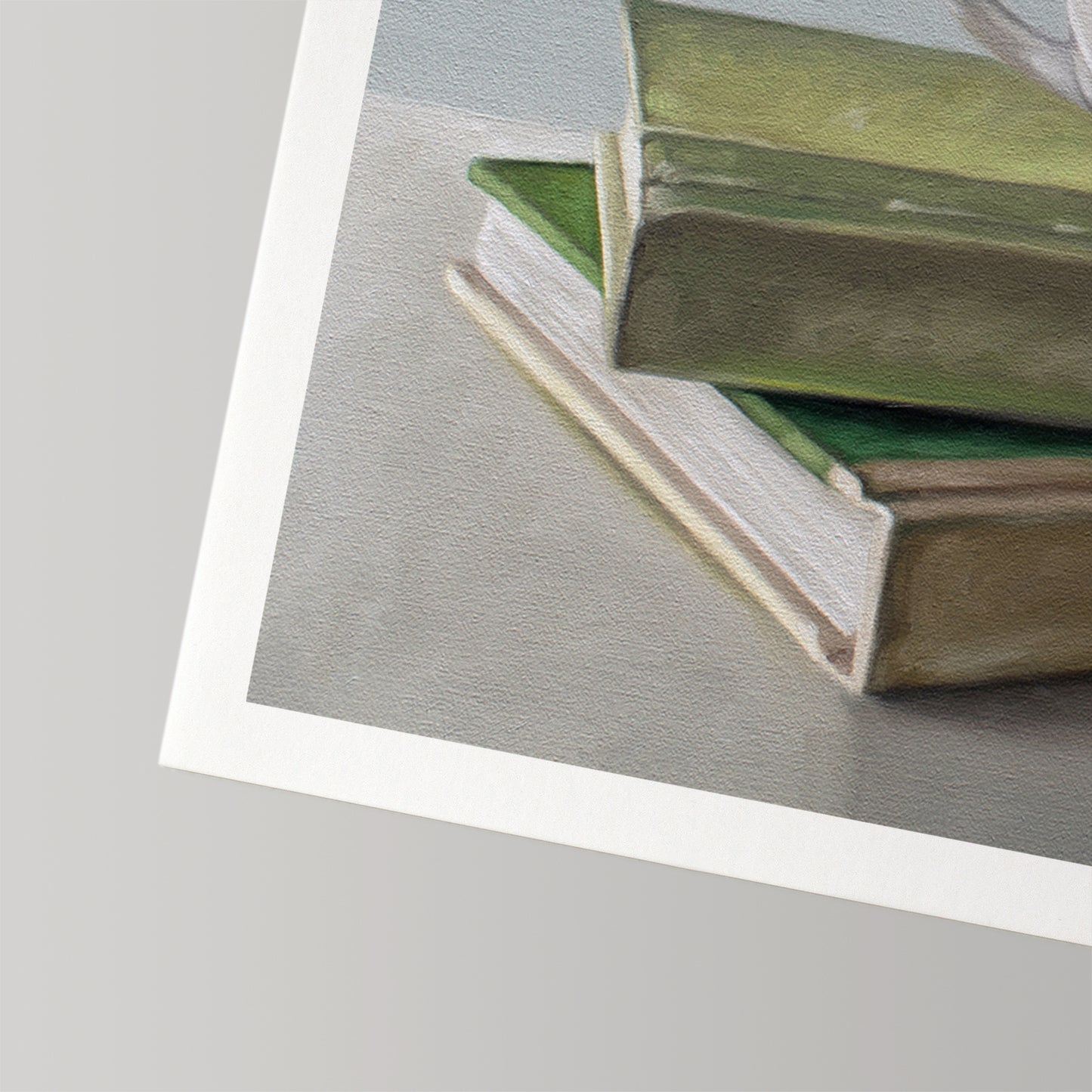 Fine art print of a stack of green and beige books on a grey surface, with a white border.