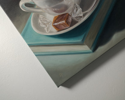 Coffee, Caramel & Book 12" x 12" Original Oil Painting by Lauren Pretorius: a white cup of coffee with a saucer on top of a book, with a piece of caramel on the saucer.