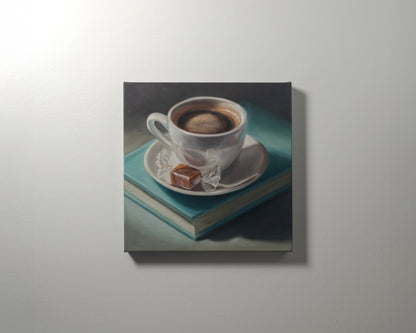 Coffee, Caramel & Book 12" x 12" Original Oil Painting by Lauren Pretorius: a white cup of coffee with a saucer on top of a book, with a piece of caramel on the saucer.