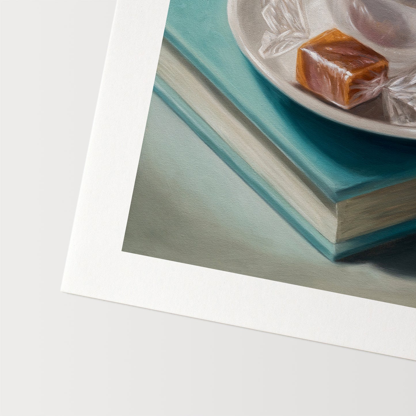 Coffee, Caramel & Books Fine Art Print by Lauren Pretorius: a white cup of coffee with a saucer on top of a book, with a piece of caramel on the saucer.