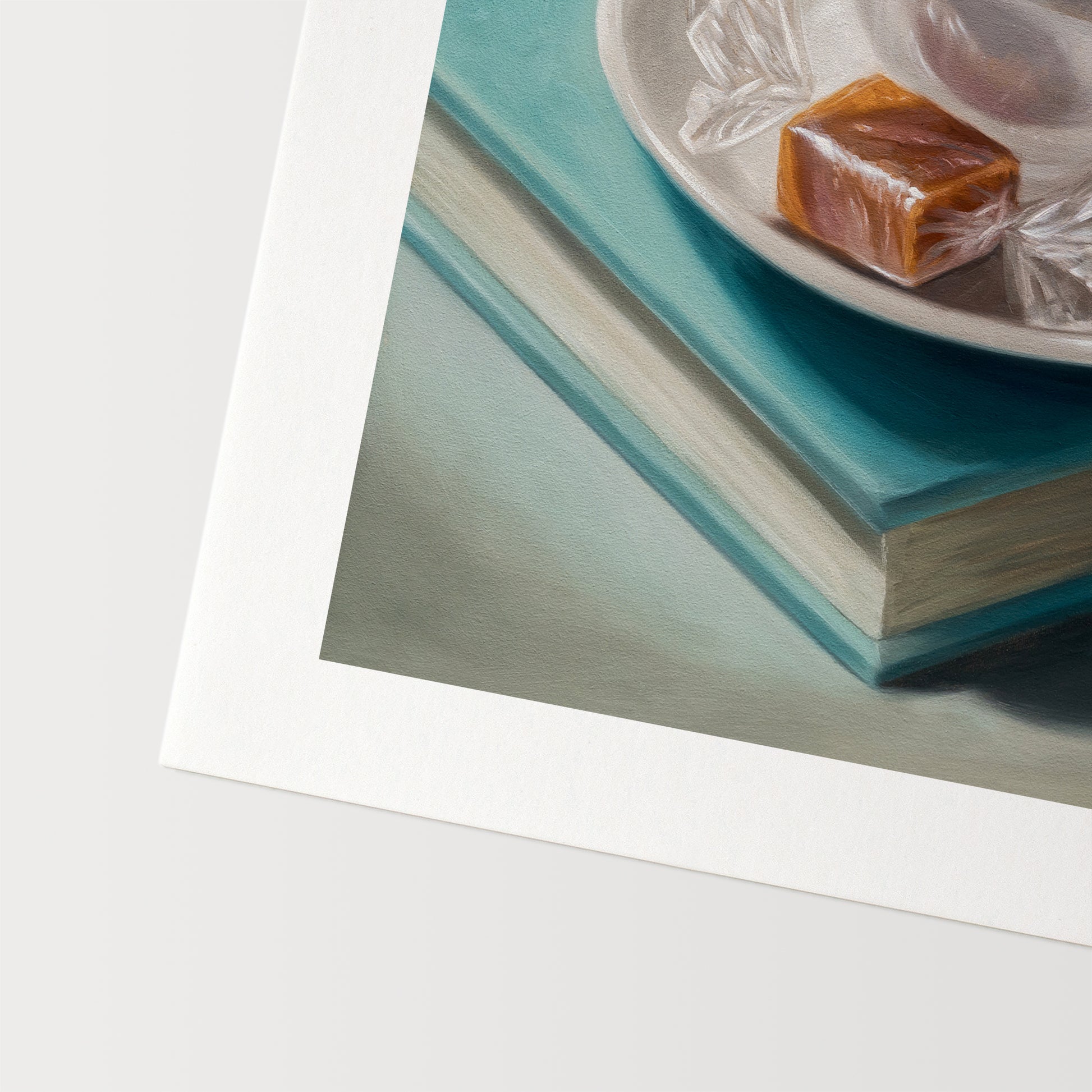 Coffee, Caramel & Books Fine Art Print by Lauren Pretorius: a white cup of coffee with a saucer on top of a book, with a piece of caramel on the saucer.