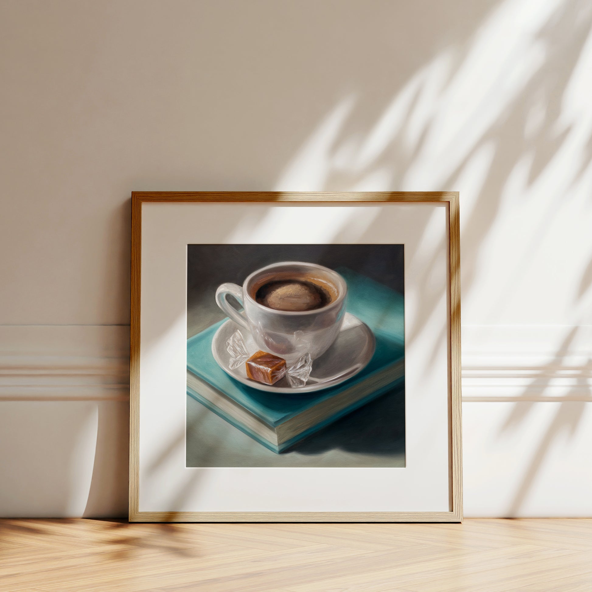 Coffee, Caramel & Books Fine Art Print by Lauren Pretorius: a white cup of coffee with a saucer on top of a book, with a piece of caramel on the saucer.