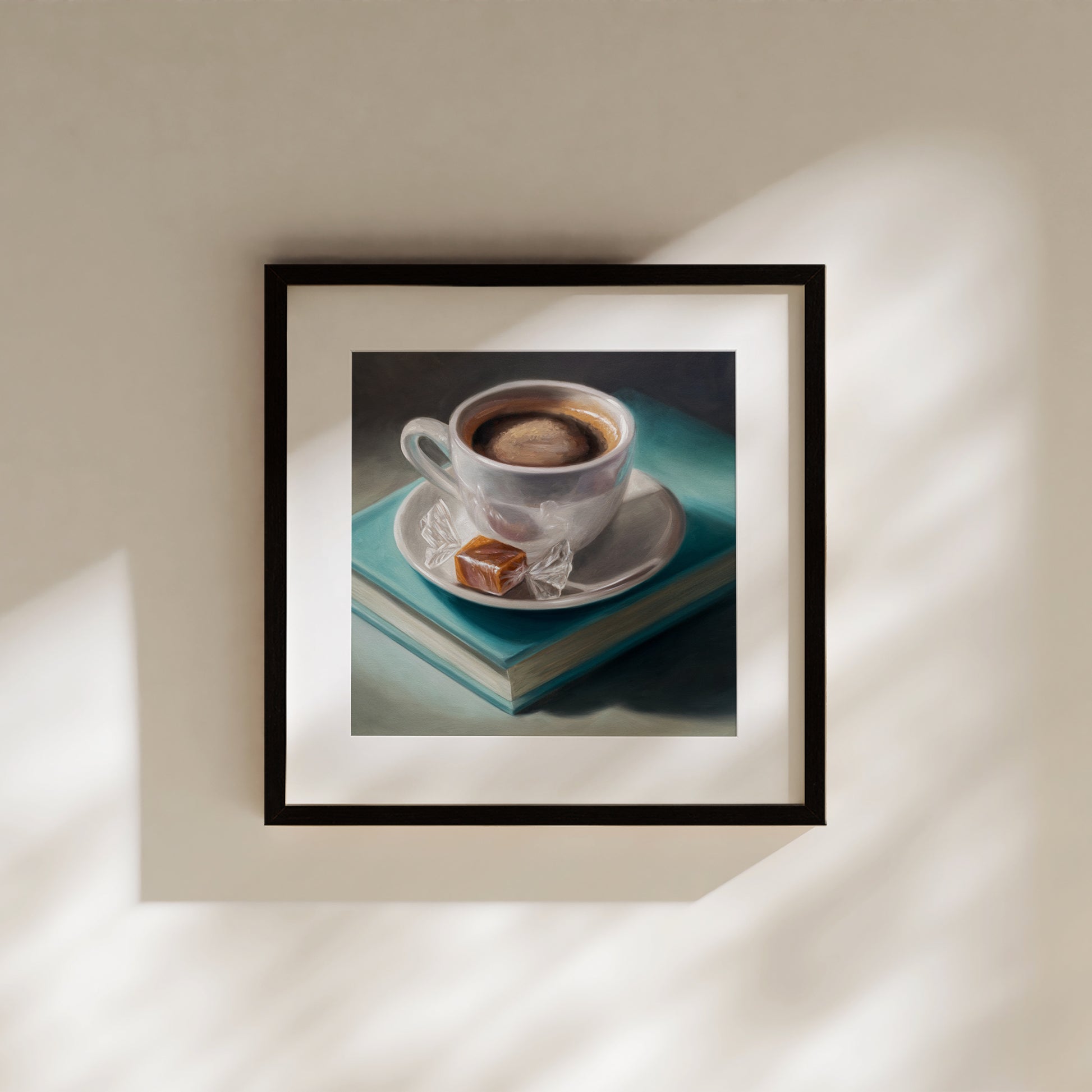 Framed fine art print of a white coffee cup, caramel candy, and a teal book on a dark background.