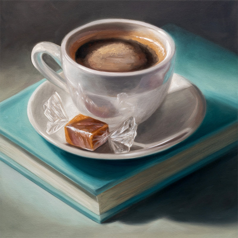 Still life painting of a white cup of coffee with a caramel candy on a saucer, resting on a teal book.