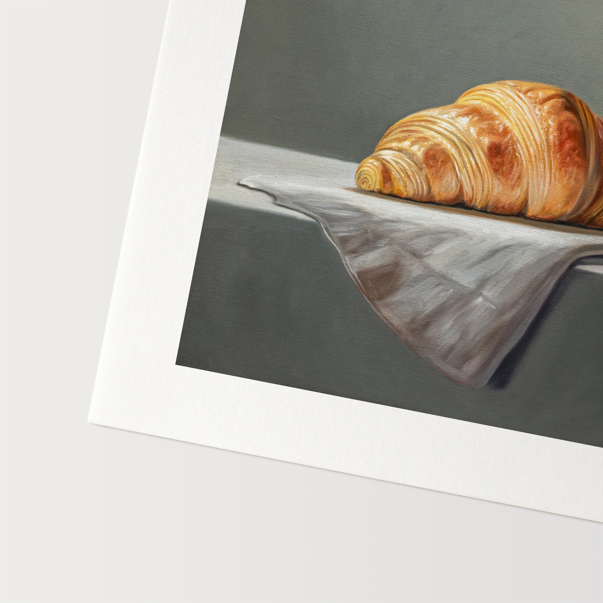 Croissant & Butter Fine Art Print by Lauren Pretorius: a croissant and a block of butter on a white surface with a grey background.