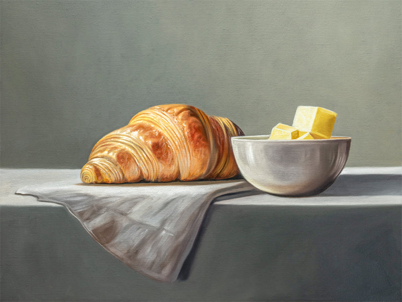 Croissant & Butter Fine Art Print by Lauren Pretorius: a croissant and a block of butter on a white surface with a grey background.