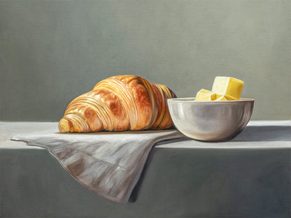 Croissant & Butter Fine Art Print by Lauren Pretorius: a croissant and a block of butter on a white surface with a grey background.