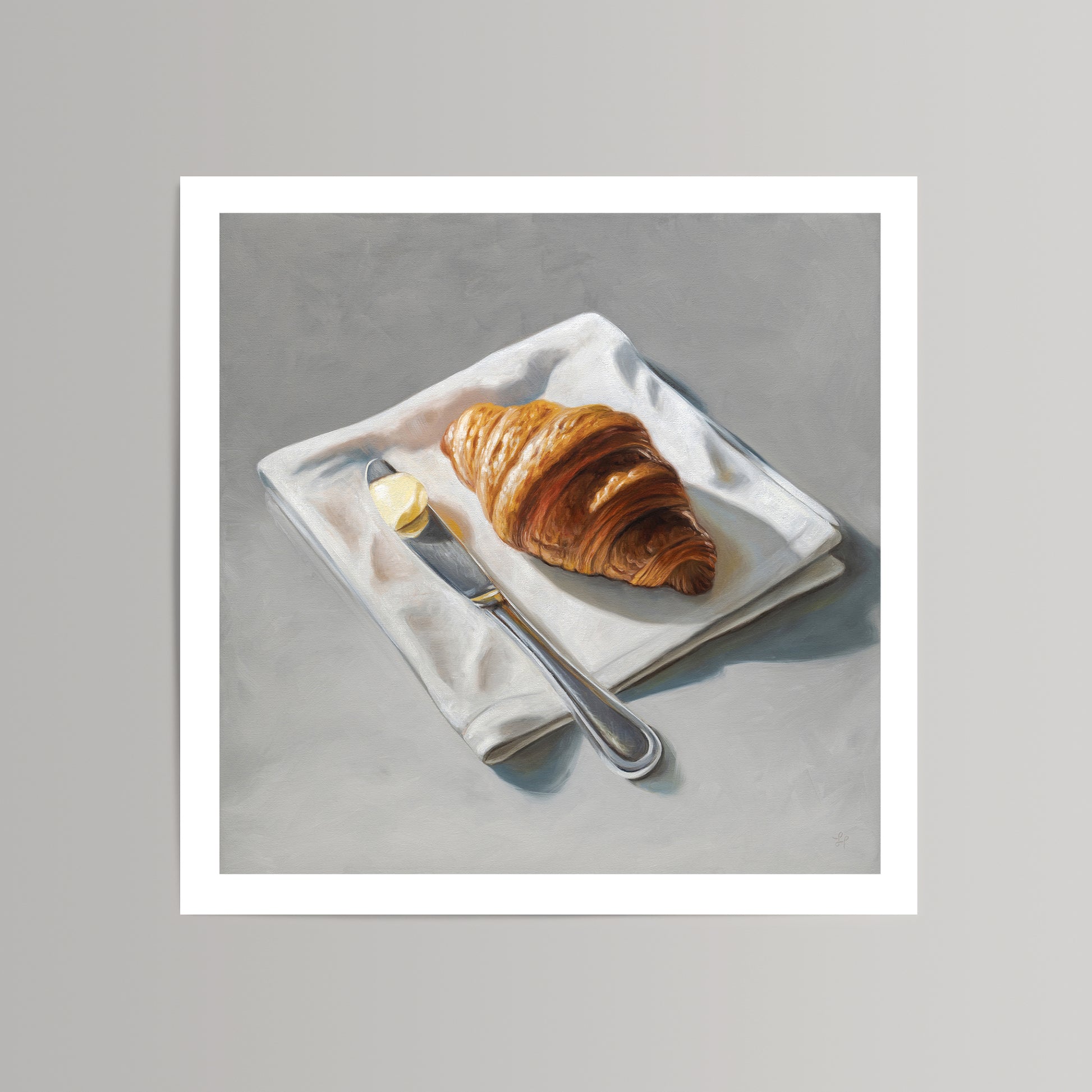 Fine art print of a golden croissant, butter pat, and silver knife on a white napkin, set against a gray background.