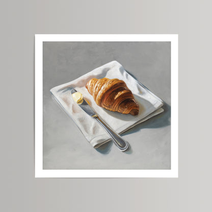 Fine art print of a golden croissant, butter pat, and silver knife on a white napkin, set against a gray background.