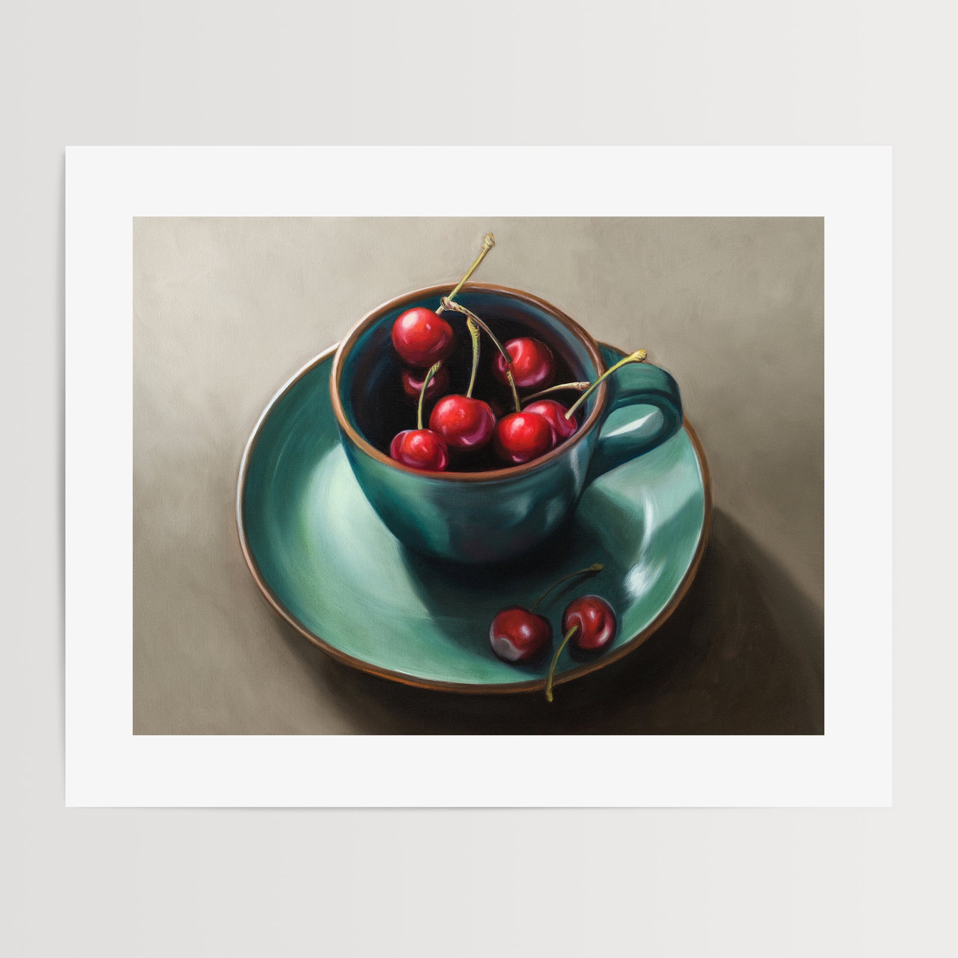 Cup of Cherries Fine Art Print by Lauren Pretorius: red cherries inside a blue green ceramic cup with a matching saucer, with a few cherries scattered outside the cup on a grey surface.