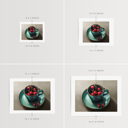 Cup of Cherries Fine Art Print by Lauren Pretorius: red cherries inside a blue green ceramic cup with a matching saucer, with a few cherries scattered outside the cup on a grey surface.