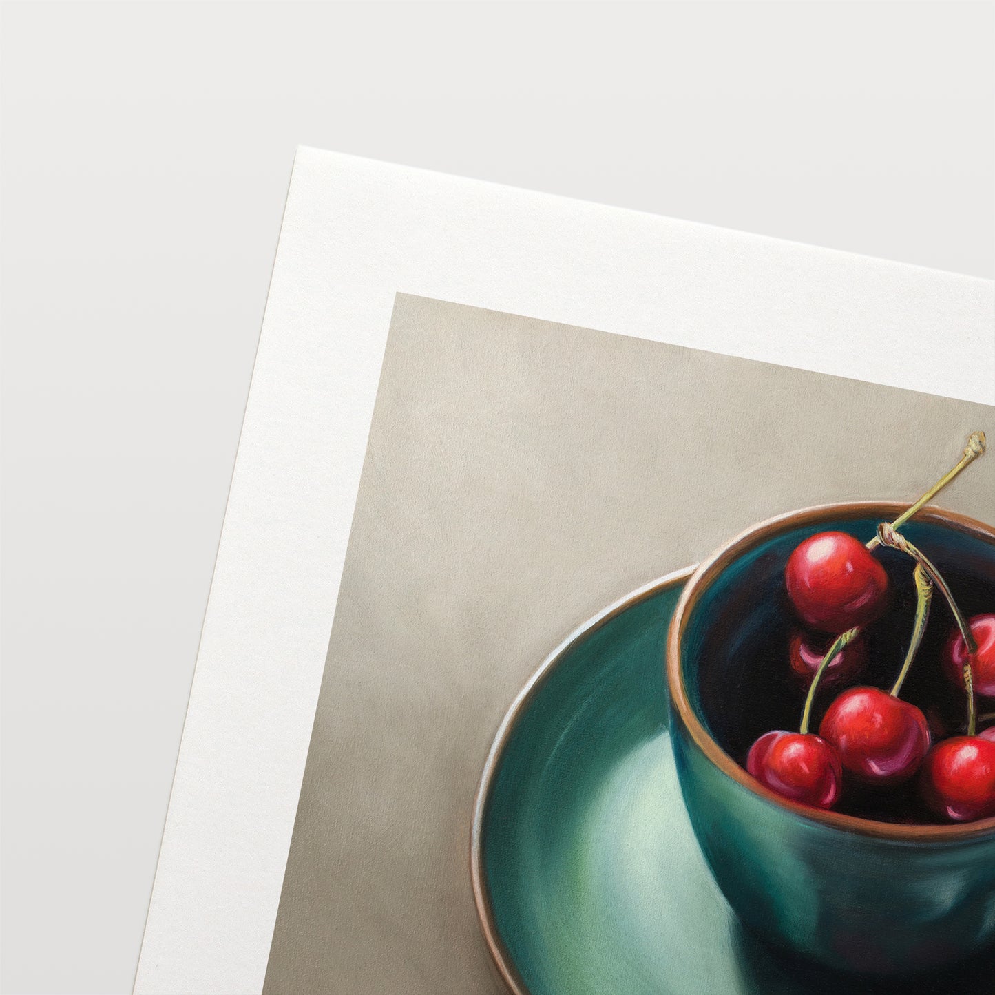 Cup of Cherries Fine Art Print by Lauren Pretorius: red cherries inside a blue green ceramic cup with a matching saucer, with a few cherries scattered outside the cup on a grey surface.