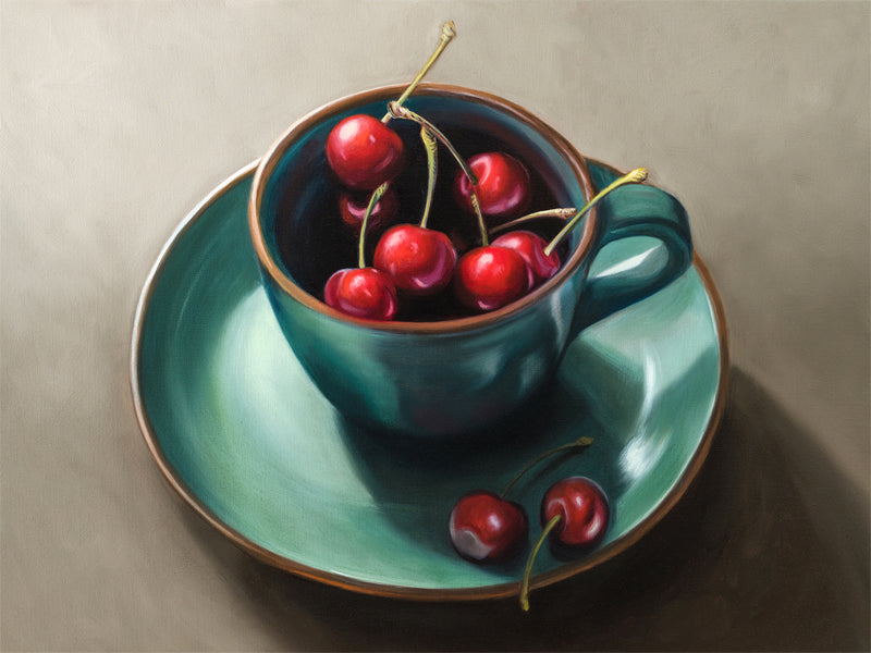 Cup of Cherries Fine Art Print by Lauren Pretorius: red cherries inside a blue green ceramic cup with a matching saucer, with a few cherries scattered outside the cup on a grey surface.