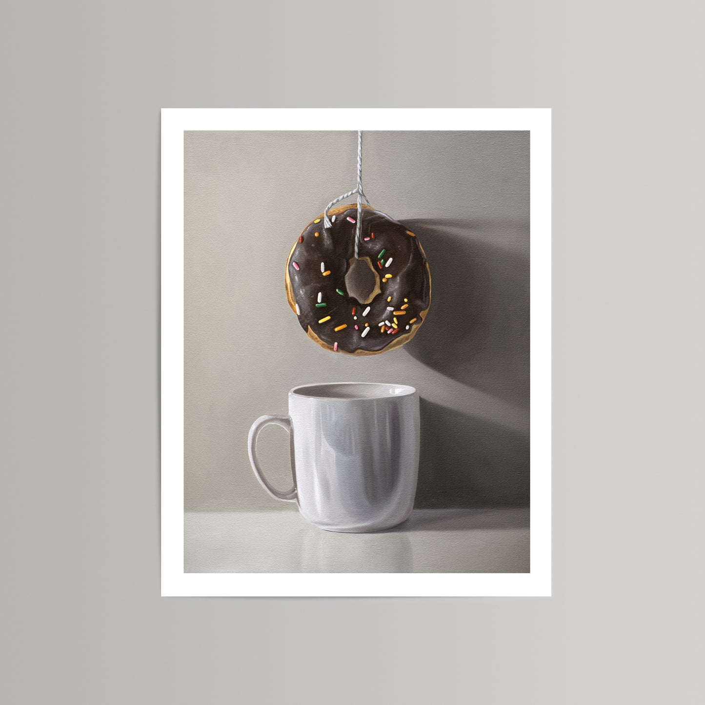 Fine art print of a chocolate donut with sprinkles hanging above a white coffee mug on a neutral background.
