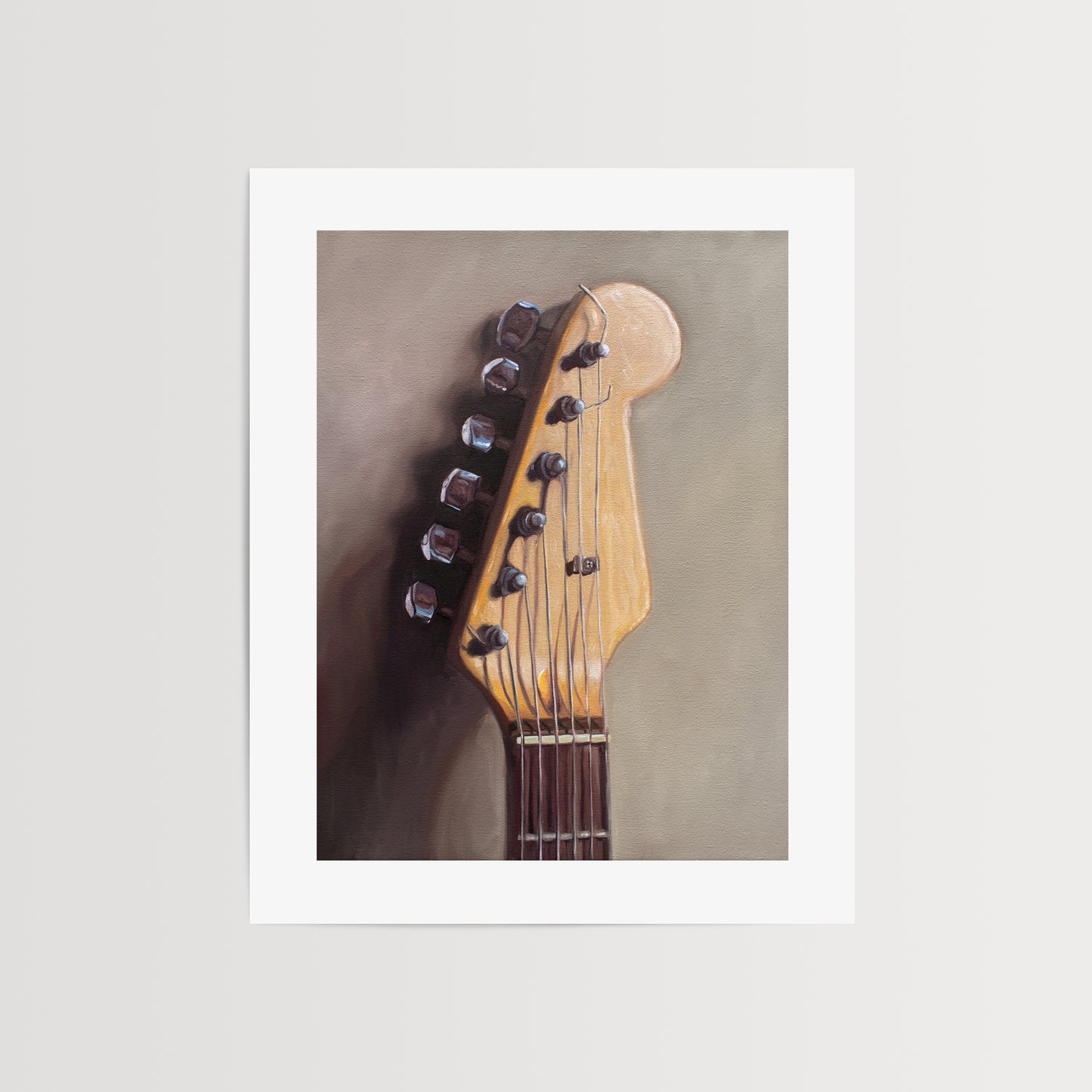 Fender Stratocaster Guitar Head Stock Fine Art Print by Lauren Pretorius: an electric guitar head stock leaning on a warm grey surface with some nice dramatic lighting.