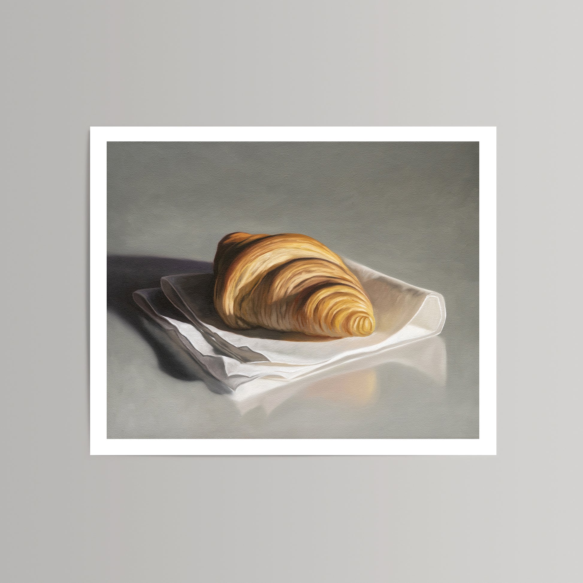 Still life fine art print of a golden croissant on a white napkin, set against a grey background.