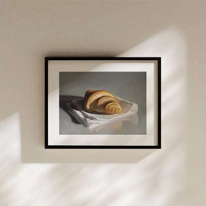 Framed art print of a golden croissant on a white napkin, with soft shadows.