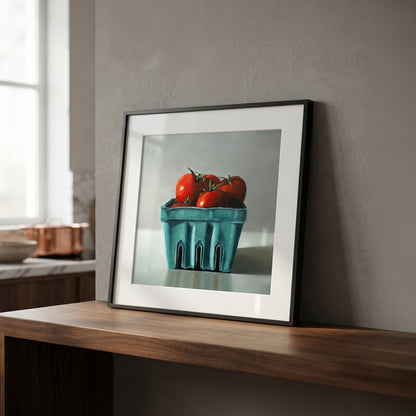 Framed fine art print of red tomatoes in a teal berry basket, displayed on a wooden shelf.