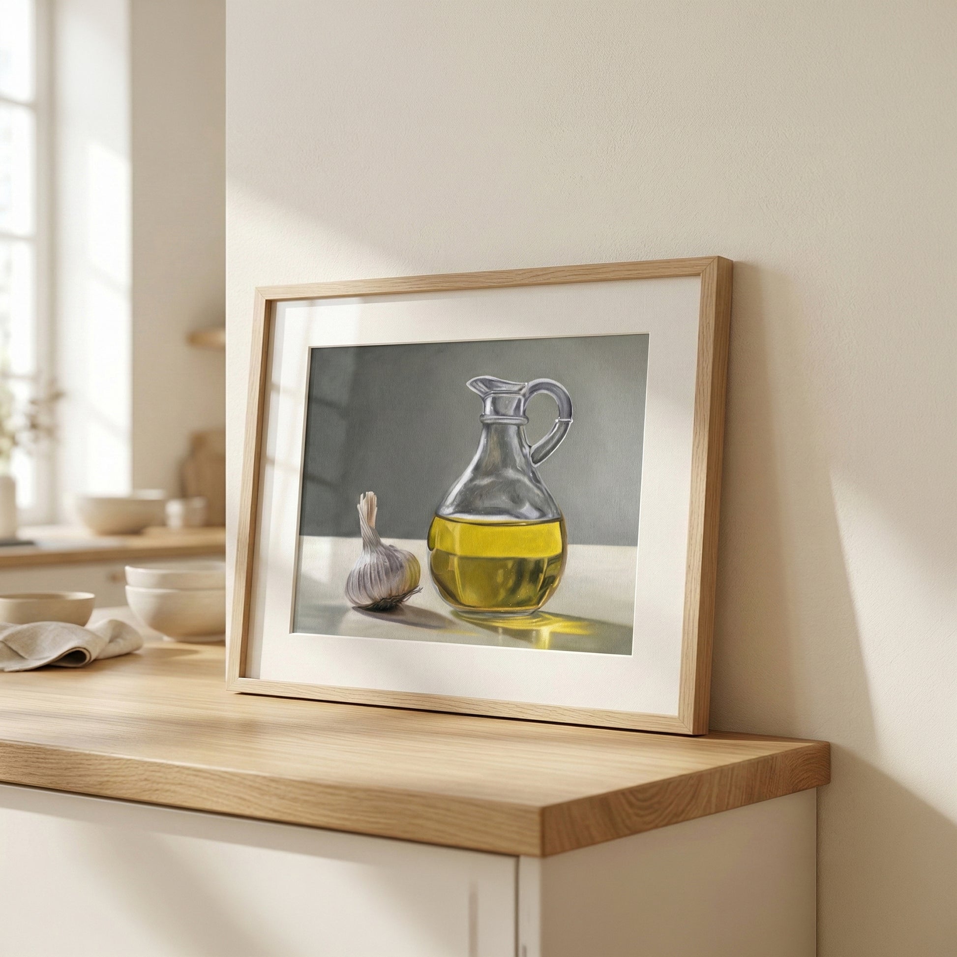 Framed fine art print of a glass carafe of olive oil and a garlic bulb on a wooden counter.
