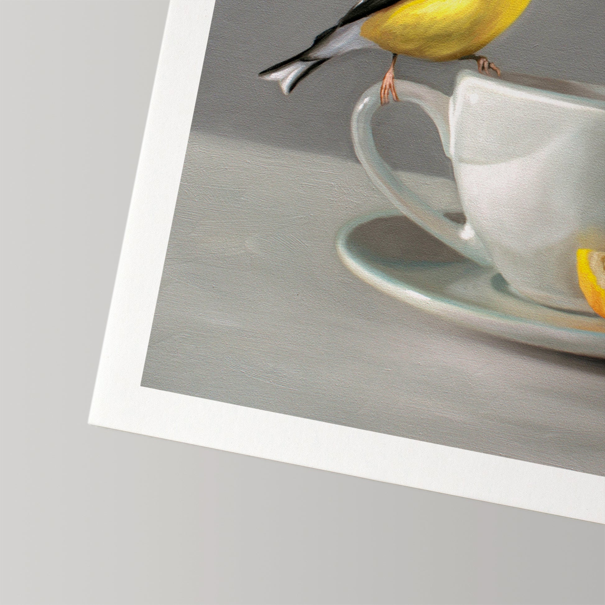 Fine art print of a yellow goldfinch perched on a white teacup with a lemon slice.