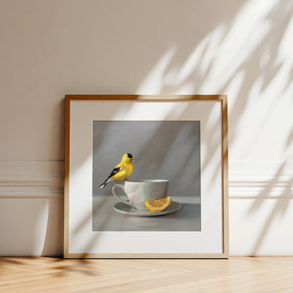 Framed fine art print of a vibrant yellow goldfinch perched on a white teacup with a lemon slice.